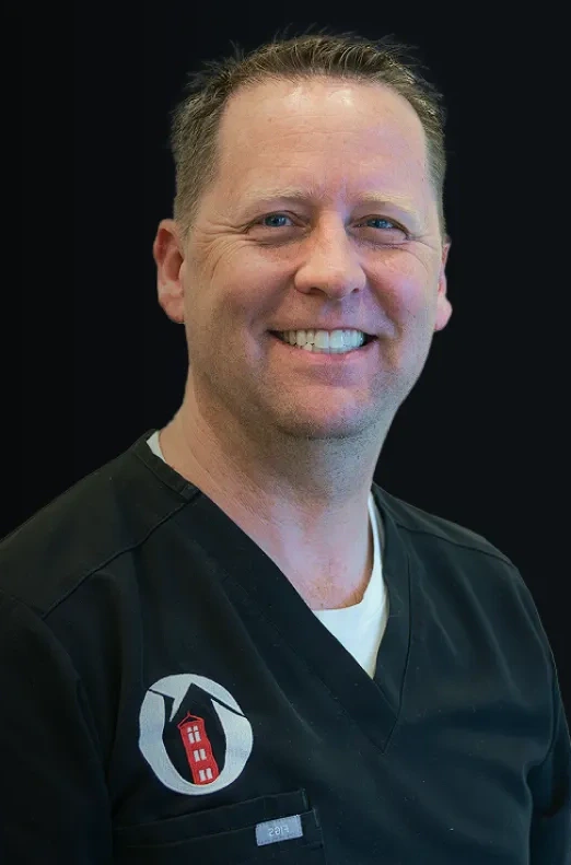 Dr. Brian Call, DDS, smiling in a black scrub top